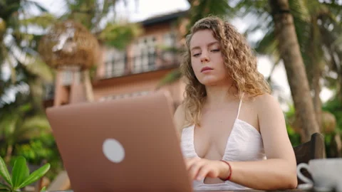 Female developer working on laptop by the ocean. Young woman freelancer coding Stock Footage 234431462