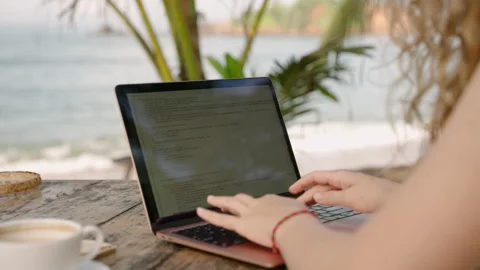 Female developer working on laptop by the ocean. Young woman freelancer coding Stock Footage 235657538