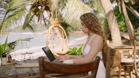 Female developer working on laptop by the ocean. Young woman freelancer coding Stock Footage 235787230