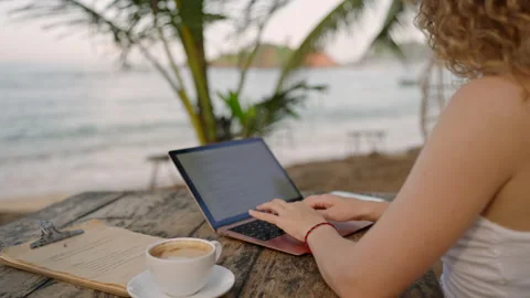 Female developer working on laptop by the ocean. Young woman freelancer coding Stock Footage 236889375
