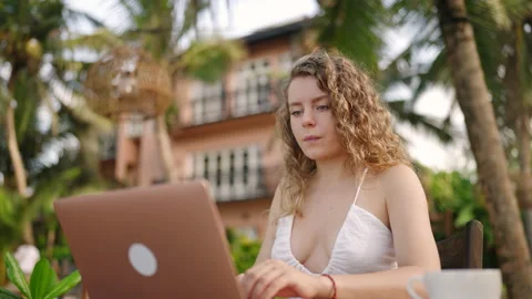 Female developer working on laptop by the ocean. Young woman freelancer coding Stock Footage 238848099