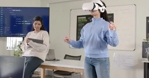 Female developers working in lab, one holding tablet while other activating Stock Footage 341063499