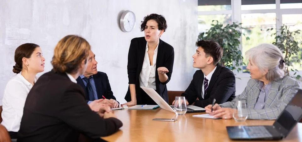 Female director gives instructions to managers in deliberation room Stock Photos