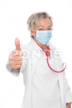 Female doctor with breathing mask is lifting thumbs up, isolated in front of whi Stock Photos
