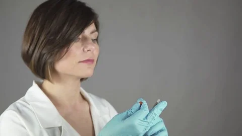 Female doctor carefully preparing an injection isolated on grey background Stock Footage