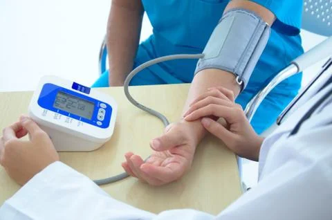 A female doctor checking blood pressure of a patient in the hospital Stock Photos
