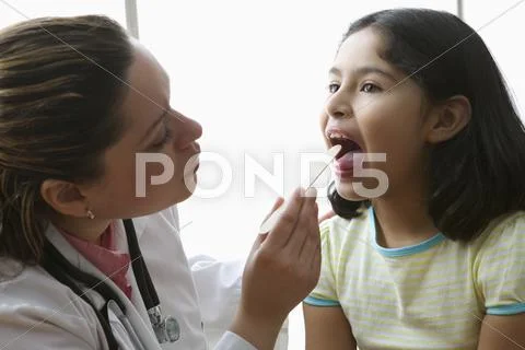 Female doctor checking girl's tonsils Stock Photos