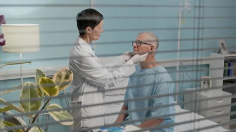 Female Doctor Checking Tonsils of Senior Patient in Ward Stock Footage 303876880