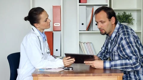 Female doctor explaining something on tablet computer to male patient Stock Footage 8852610