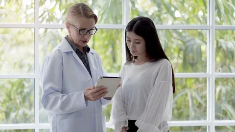 Female doctor is explaining something using the information in the tablet Stock Footage 97998825