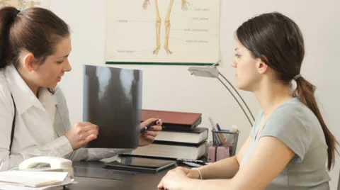 Female doctor explaining x-ray image to patient - tracking shot Stock Footage 22938939