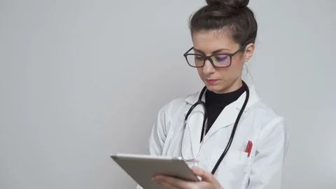 Female doctor with glasses using tablet to register patients for coronavirus Stock Footage 126398580