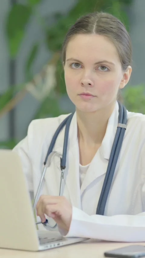 Female Doctor Looking at Camera while using Laptop, vertical video Video stock 329108292
