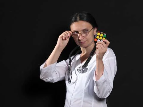 A female doctor solves a complex puzzle by posing on a black background Stock Photos