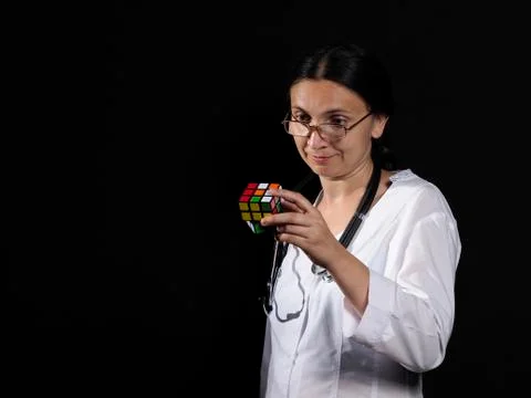 A female doctor solves a complex puzzle by posing on a black background Stock Photos