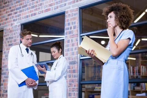 Female doctor thinking while checking a file near library Stock Photos