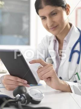 Female Doctor Updating Medical Records Using Digital Tablet