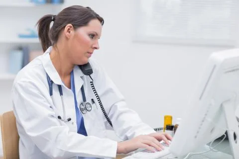 Female doctor using computer while on call at clinic 스톡 사진