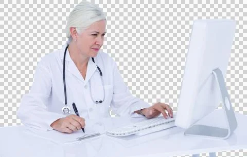 Female doctor using computer while writing on clipboard at desk Stockfoto's