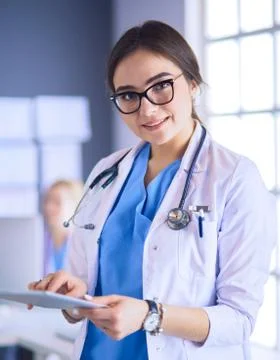 Female doctor using tablet computer in hospital lobby Stock Photos