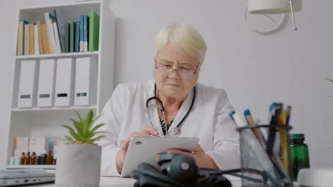Female doctor using tablet to process patients data for medical analysis. Stock Footage 299633172