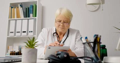 Female doctor using tablet to process patients data for medical analysis. Stock Photos
