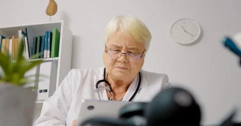 Female doctor using tablet to process patients data for medical analysis. Stock Photos