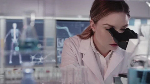 Female doctor working in laboratory. Using microscope, looking through glassware Stock Footage 149794665