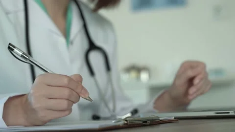 Female doctors hands using laptop and handwriting notes in medical office Stock Footage 170033096