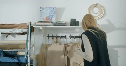 Female dressmaker choosing patterns in studio. Blond seamstress taking bunch of 스톡 동영상 149038429
