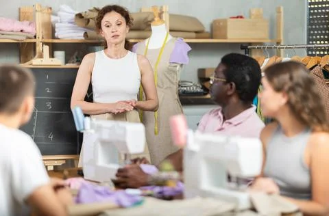 Female dressmaker explaining pattern modeling on chalkboard during course for Foto stock