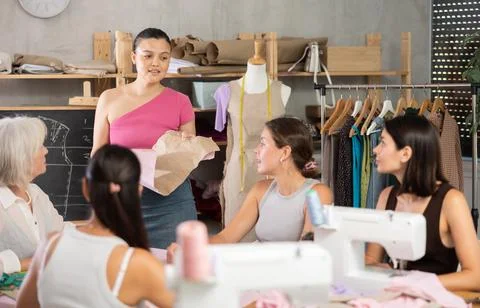 Female dressmaker explaining pattern modeling by chalkboard during course for Stock Photos