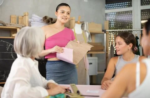 Female dressmaker explaining pattern modeling by chalkboard during course for Stock Photos