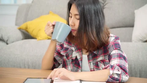 Female drinking coffee and using tablet for searching on sofa at home. Stock Footage 110351988