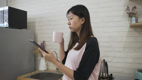 Female drinking coffee is scrolling down the page Stock Footage 163693050