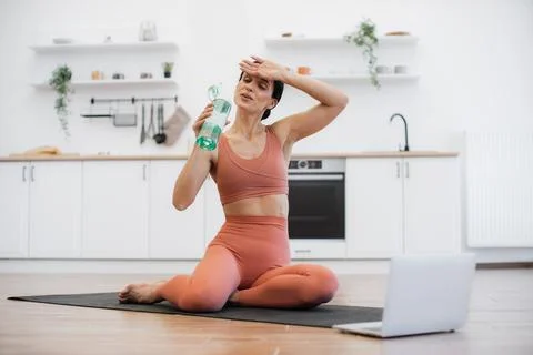 Female drinking cold water while exercising on yoga mat Stock-Fotos