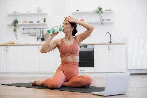 Female drinking cold water while exercising on yoga mat 스톡 사진