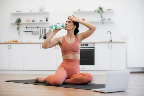 Female drinking cold water while exercising on yoga mat Stock-Fotos