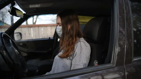 A female driver puts on a face mask and gloves in the car Stock Footage 131143255