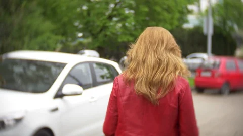 A female driver in a red jacket sits down in the car. 4K Stock Footage 88621727