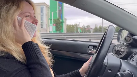 Female driver talking on the phone while driving, road safety, fine Stock Footage 252020663