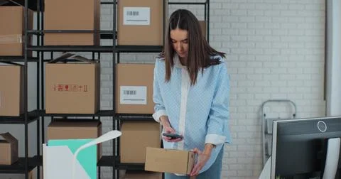 Female e-commerce worker using computer and smartphone at work preparing boxes Stock Photos