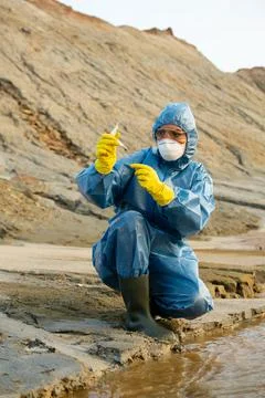 Female ecologist looking at flask with sample of dirty water or soil in Fotos de archivo