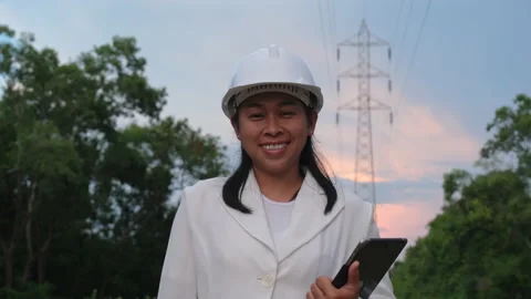Female electrical engineer holding tablet and smiling near high voltage pole Stock Footage 204970003