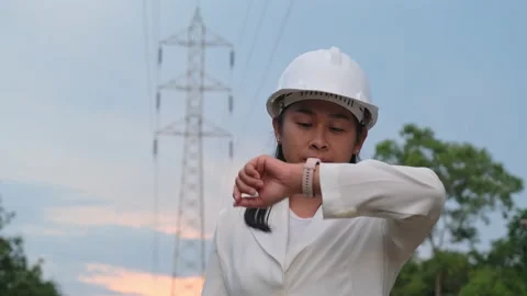 Female electrical engineer looking at a smart watch on high voltage background Stock Footage 204971139