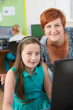 Female elementary pupil in computer class with teacher Stock Photos