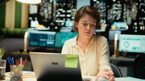 Female employee checking the time on her phone and closing laptop Stock Footage 317962633