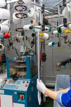 A female employee performs visual quality control of hosiery. Фото