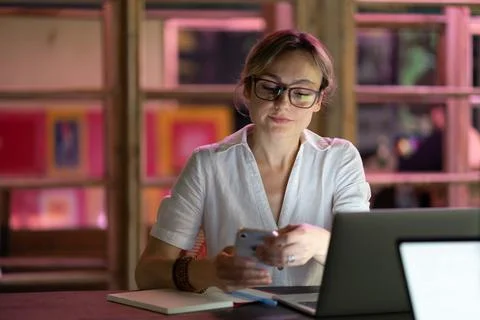 Female employee using mobile device at workplace, young woman freelancer Stock Photos