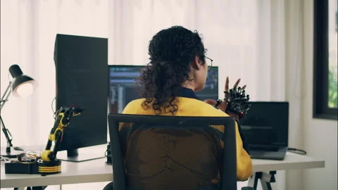 Female engineer analyzing robotic hand while coding in modern tech lab. Video stock 307586912